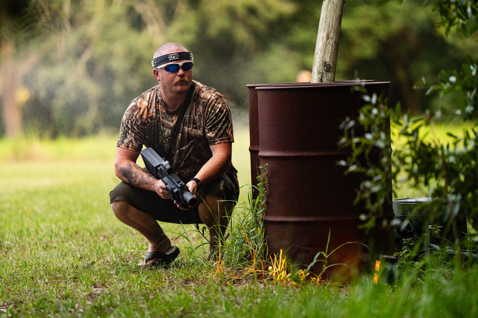 Adult player crouching beside battlefield cover with a laser tagger