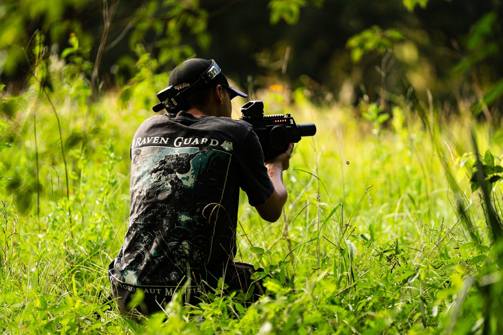 Player aiming a laser tagger while moving through tall grass