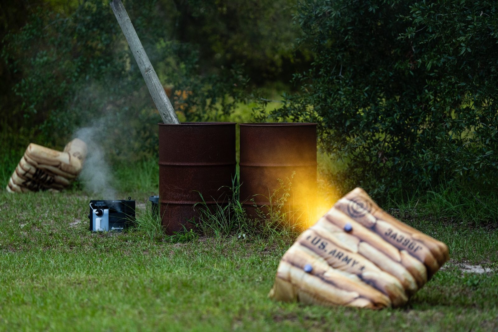 Outdoor laser-tag battlefield with inflatable cover, barrels, and colored effects