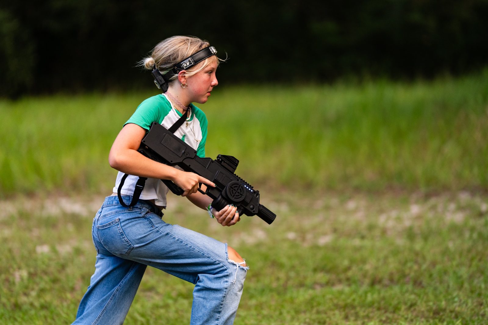 Player moving across an outdoor field with a laser tagger