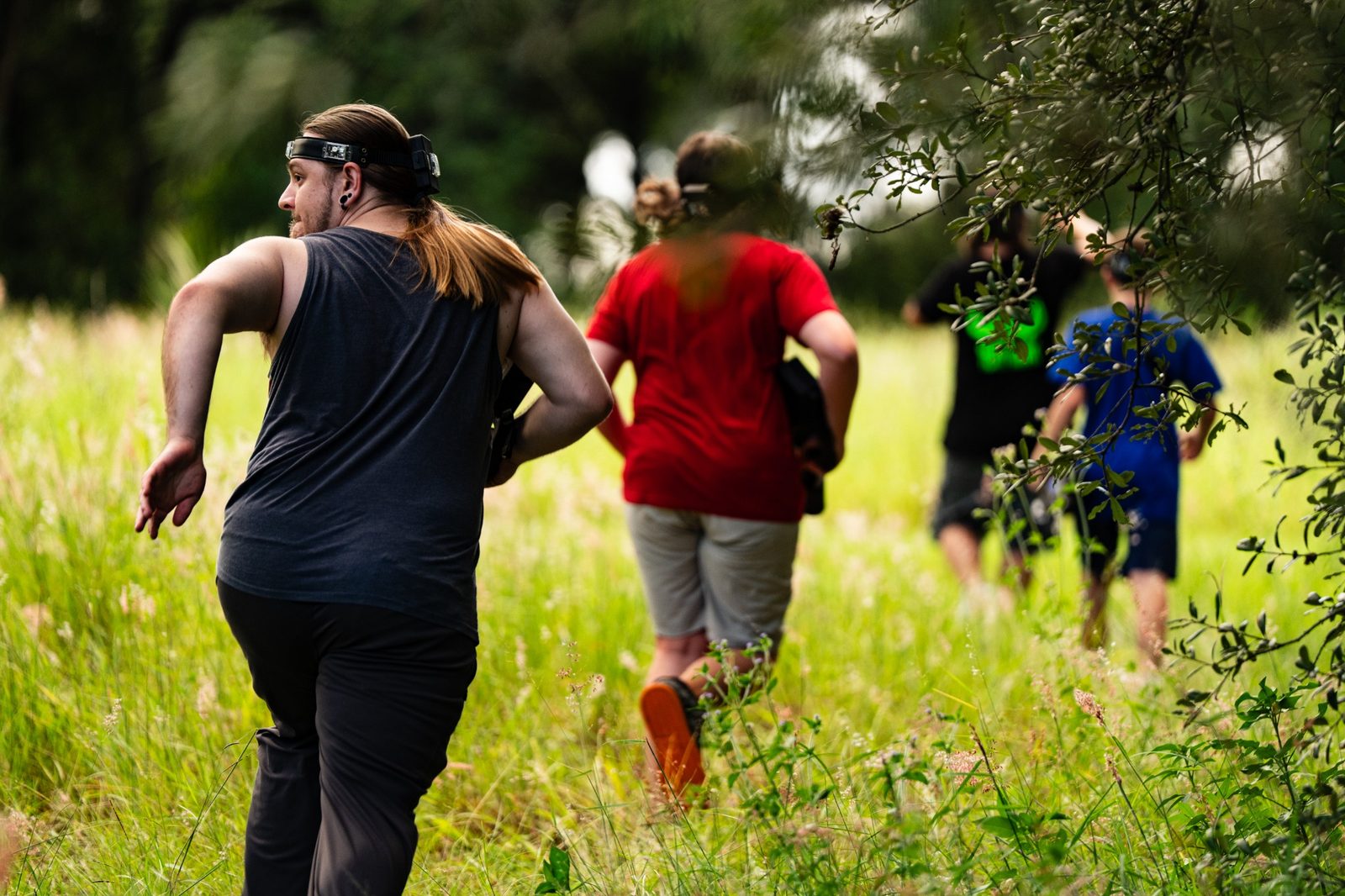Group of laser-tag players running through a grassy outdoor course
